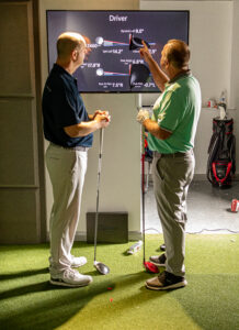 2 golfers looking at the Trackman data from their swing in the Next Level Golf studio